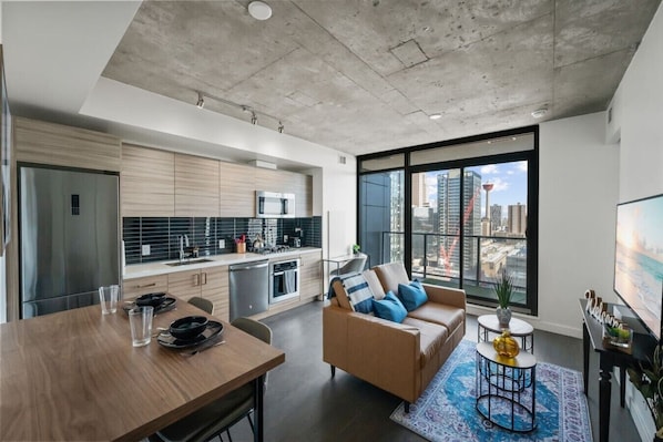 A modern apartment with a kitchen, dining area, and living room with a city view.