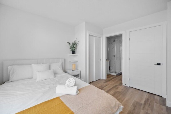 Un dormitorio con cama, mesita de noche y una planta en maceta.