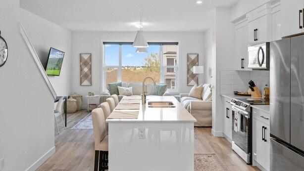 A modern kitchen with a central island, stainless steel appliances, and a large window offering a view of the outdoors.