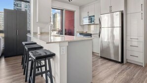 Une cuisine moderne dotée d’un îlot central, d’appareils électroménagers en acier inoxydable et offrant une vue sur la ville.