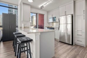Een moderne keuken met een centraal eiland, roestvrijstalen apparatuur en uitzicht op de stad.