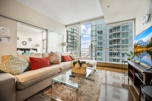 Uma sala de estar moderna com sofá, mesa de centro e uma janela grande com vista para a cidade.