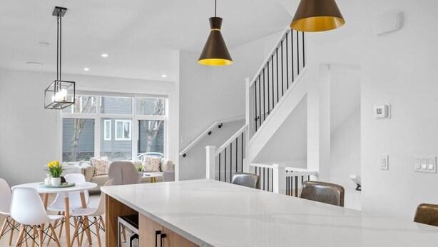 A modern kitchen with a large island, white cabinetry, and pendant lighting. - King Bed | Ping Pong | 3BR | Garage | AC |Backyard (Calgary)