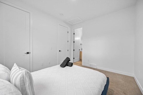 A bedroom with a bed, pillows, and a door leading to a bathroom.