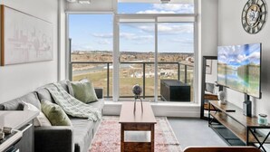 Una sala de estar moderna con un gran ventanal, televisor de pantalla plana y vista a un paisaje.