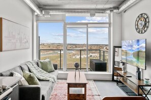 Una sala de estar moderna con un gran ventanal, televisor de pantalla plana y vista a un paisaje.