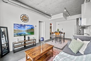 Una sala de estar moderna con televisor de pantalla plana, una mesa de centro de madera y un sofá.