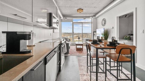 Una cocina moderna con cafetera, mesa de comedor, sillas y vistas por la ventana.
