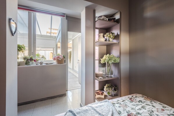 Un dormitorio con cama, una ventana con plantas y una estantería con adornos.