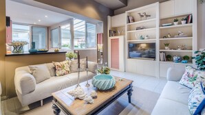 Un salon moderne avec un canapé, une table basse et des étagères intégrées ornées d’objets décoratifs.