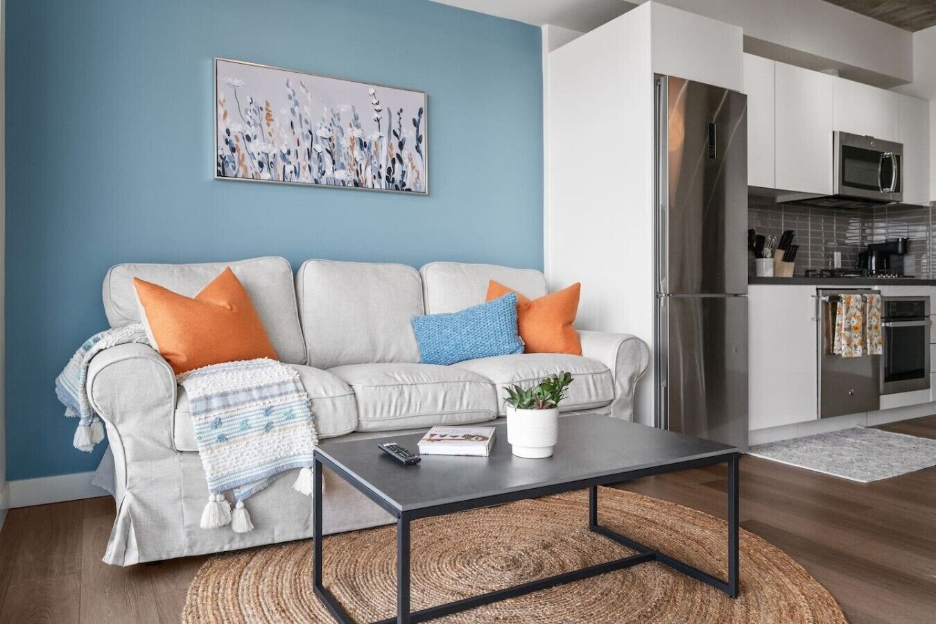 A living room with a sofa, coffee table, and a painting on the wall.