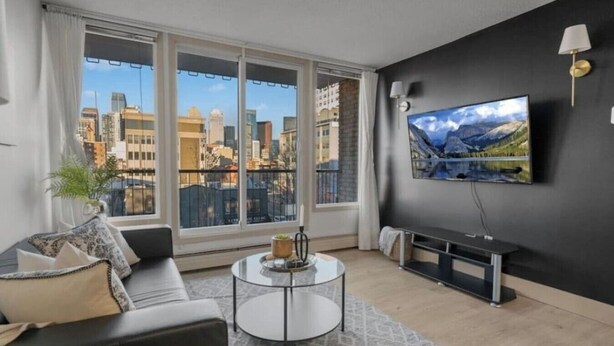 Una sala de estar moderna con un ventanal grande, un televisor de pantalla plana, un sofá y una mesa de centro.
