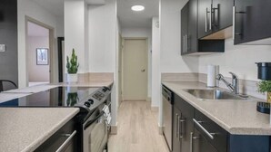 Una cocina moderna con estufa, horno, pileta y alacenas oscuras.