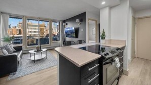 Un apartamento moderno con isla de cocina, comedor y ventanas amplias con vistas a la ciudad.