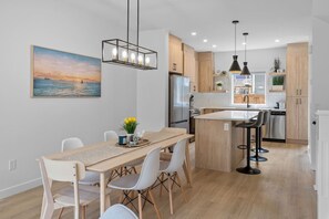 Una cocina moderna con armarios de madera, un refrigerador de acero inoxidable y una isla central con taburetes de bar.