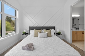 Un dormitorio con una cama grande, dos mesitas de noche, un cabecero y vistas al exterior.