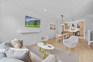 Una sala de estar moderna con televisor de pantalla plana, un comedor y una cocina.