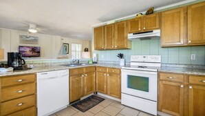 A kitchen with wooden cabinets, a dishwasher, a stove, and a coffee maker. - Dock * Water Views * Deck * Nature * Sunsets (Cedar Key)