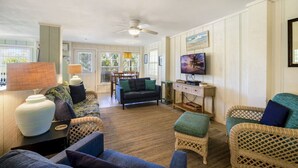 A living room with wicker furniture, a ceiling fan, and a television on the wall. - Dock * Water Views * Deck * Nature * Sunsets (Cedar Key)