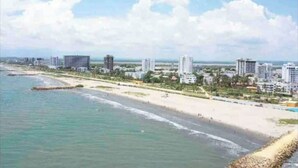 A coastal cityscape with a beach and high-rise buildings.