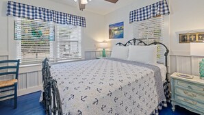 A bedroom with a bed, a chair, a dresser, and a ceiling fan.
