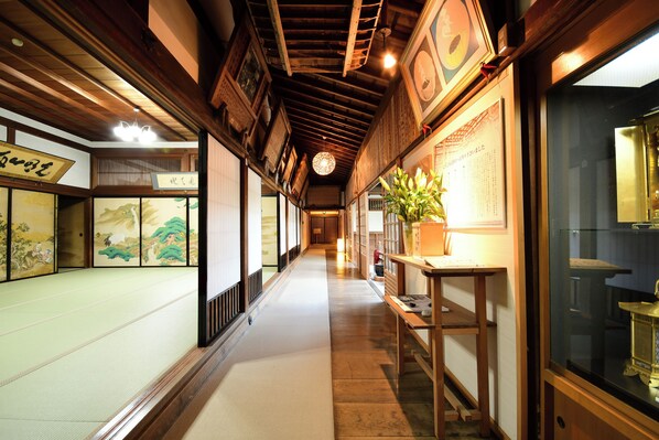 Una habitación japonesa tradicional con suelo de tatami, vigas de madera y puertas correderas shoji.