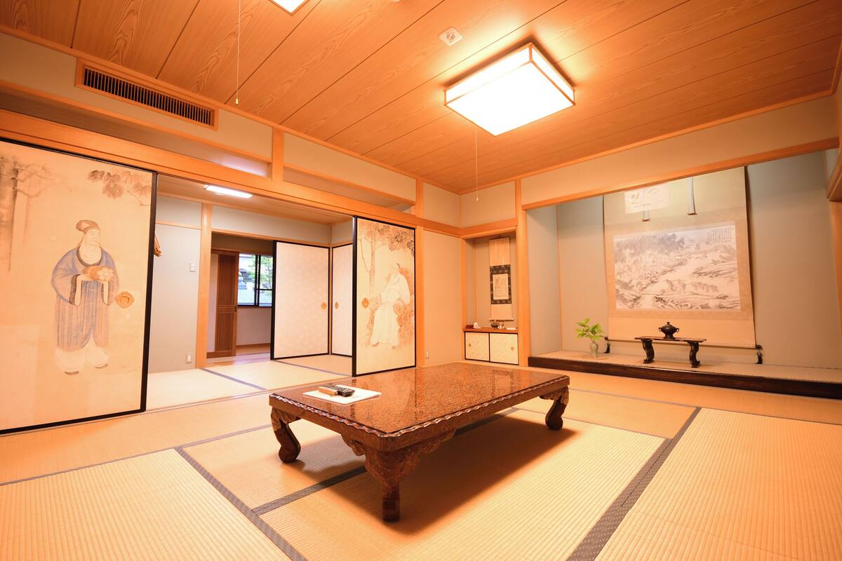Een traditionele Japanse kamer met tatami vloerbedekking, een houten tafel en kunstwerken aan de wanden.