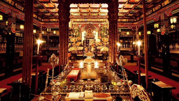 Un interior ornamentado con un altar central, rodeado de estanterías con libros y objetos decorativos.