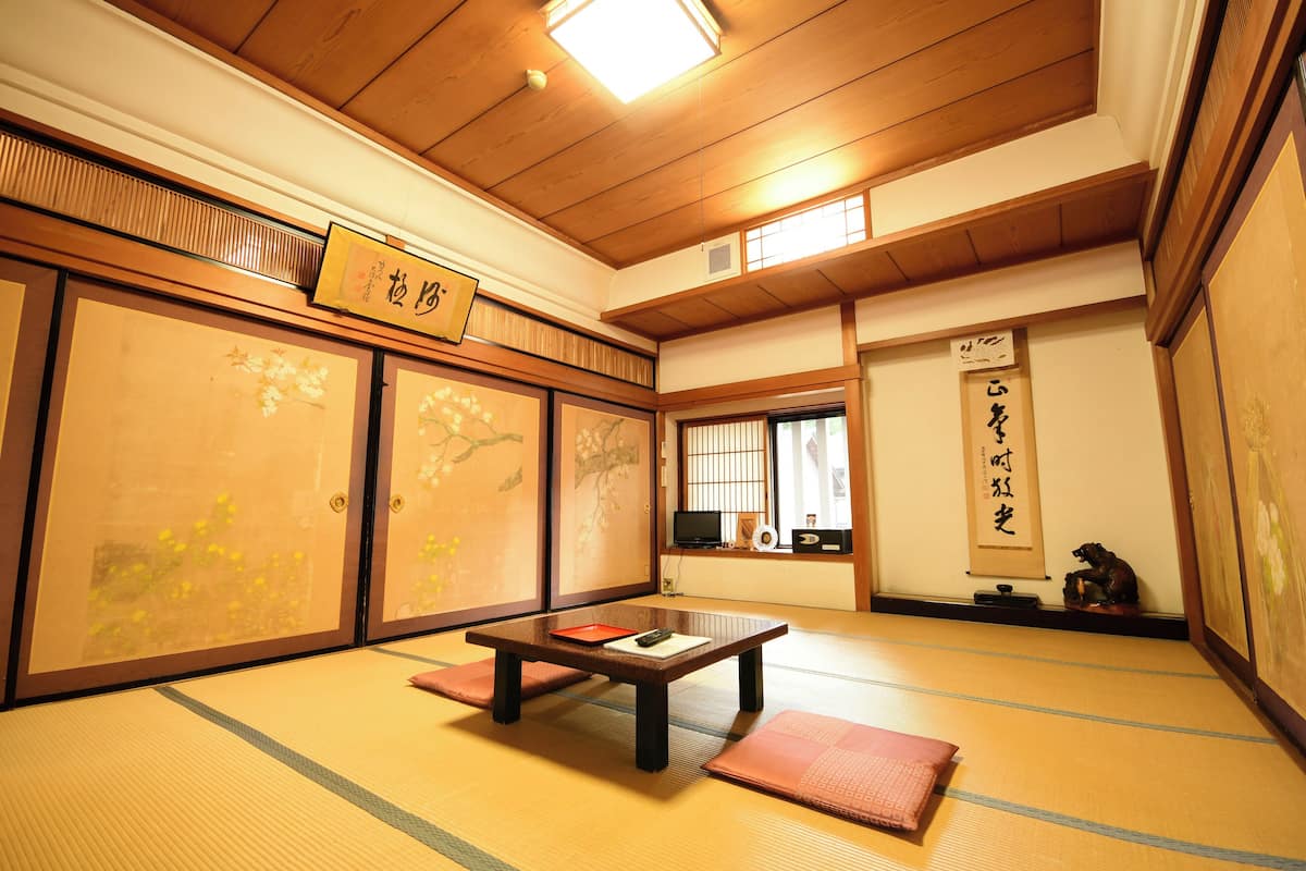 Een traditionele Japanse kamer met tatami vloerbedekking, schuifdeuren en een lage tafel met kussens.