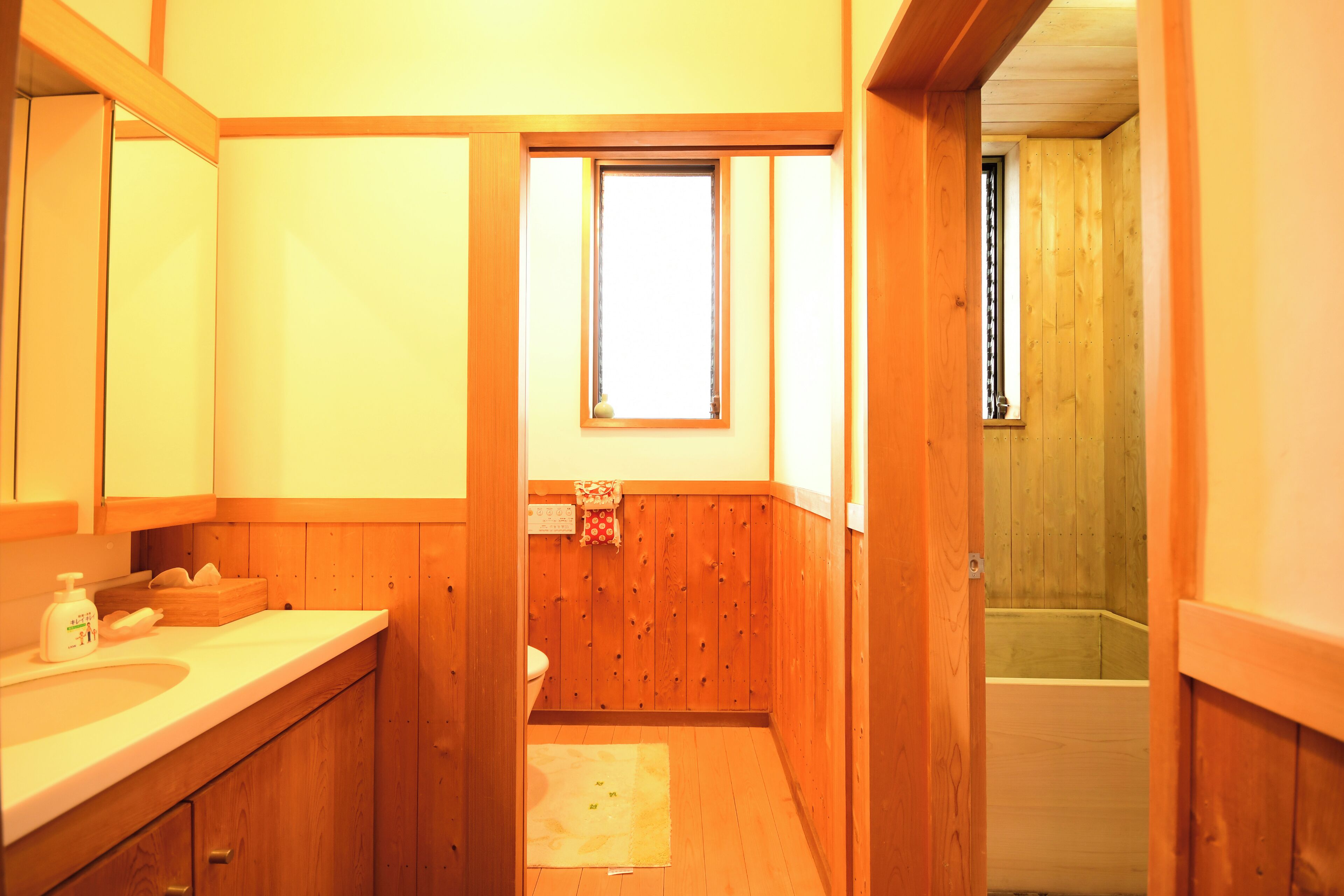 A wooden bathroom with a sink, mirror, and window.