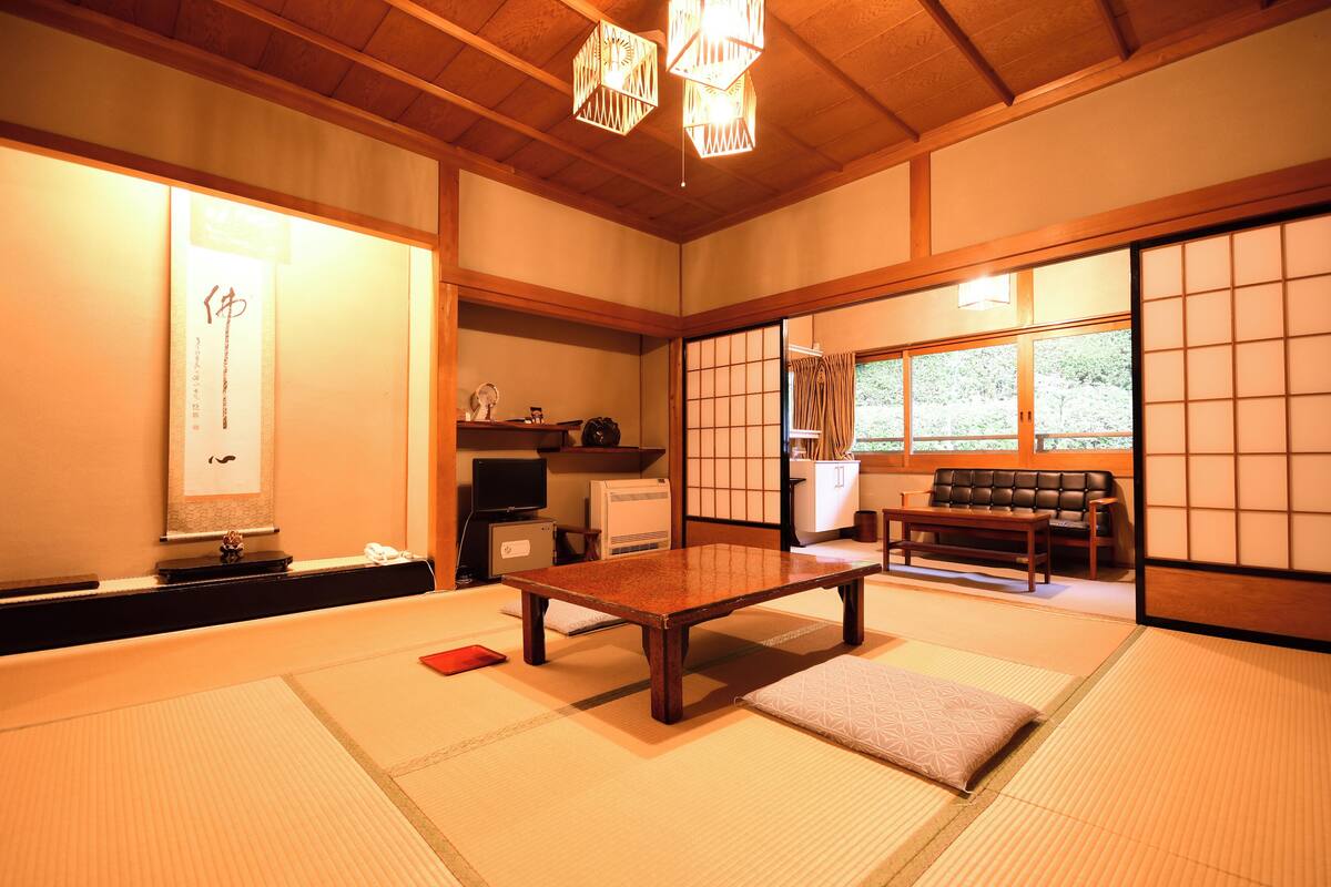 Een traditionele Japanse kamer met tatami vloeren, een lage houten tafel, een bank en schuifdeuren van shoji papier.