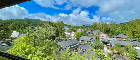 Un pueblo japonés tradicional con edificios de techo de paja, rodeado de exuberante vegetación y montañas.