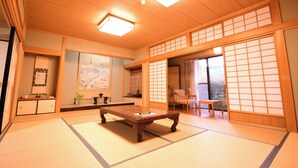 Una habitación tradicional japonesa con suelo de tatami, una mesa baja de madera, puertas correderas y vistas al exterior.