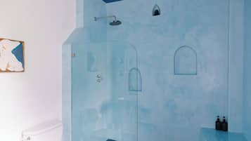 Un baño con cabina de ducha de vidrio, inodoro blanco y pared azul decorativa.
