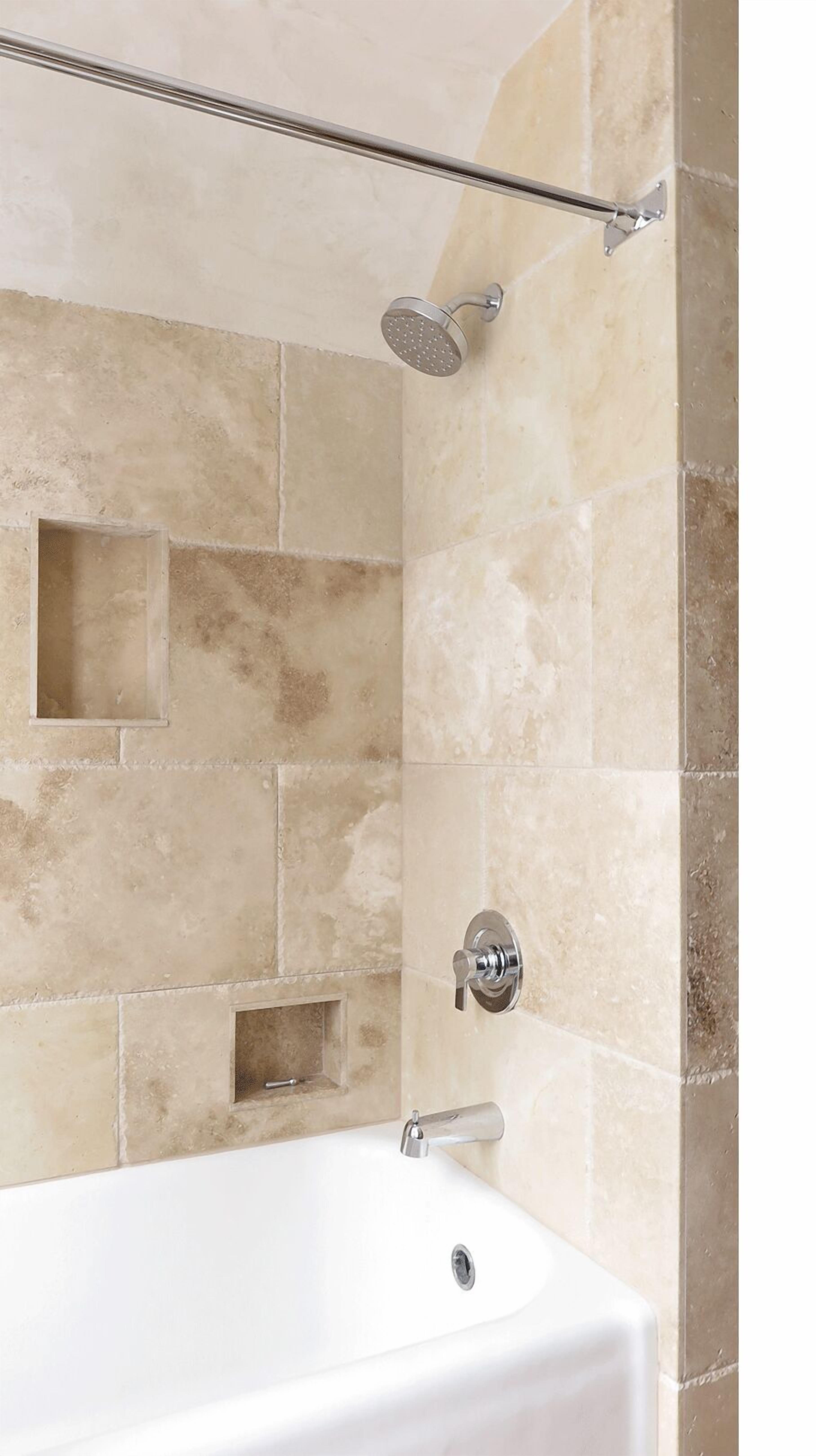 A bathroom with beige tiles, a bathtub, a showerhead, and a wall-mounted faucet.