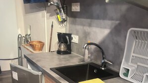 A compact kitchen with a built-in refrigerator, a sink, and a coffee maker. - Studio Montagne 20 m (Saint-Léger-les-Mélèzes)