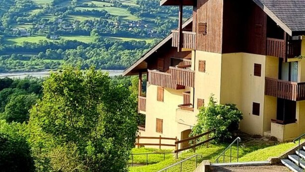 A two-story wooden building with a balcony, set against a mountainous backdrop. - Studio Montagne 20 m (Saint-Léger-les-Mélèzes)