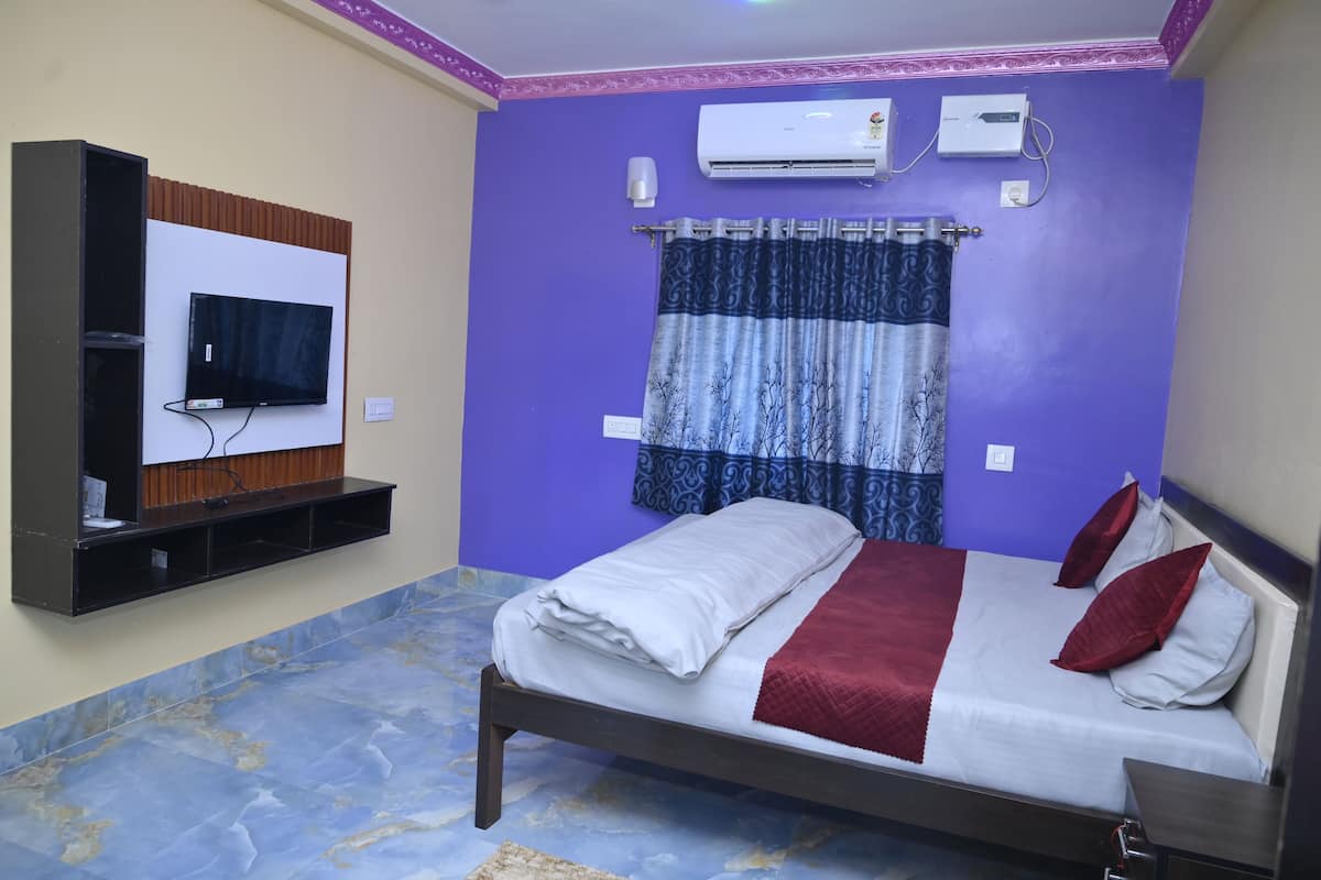 Een slaapkamer met een bed, een aan de muur bevestigde televisie, een airconditioner en een gordijn.