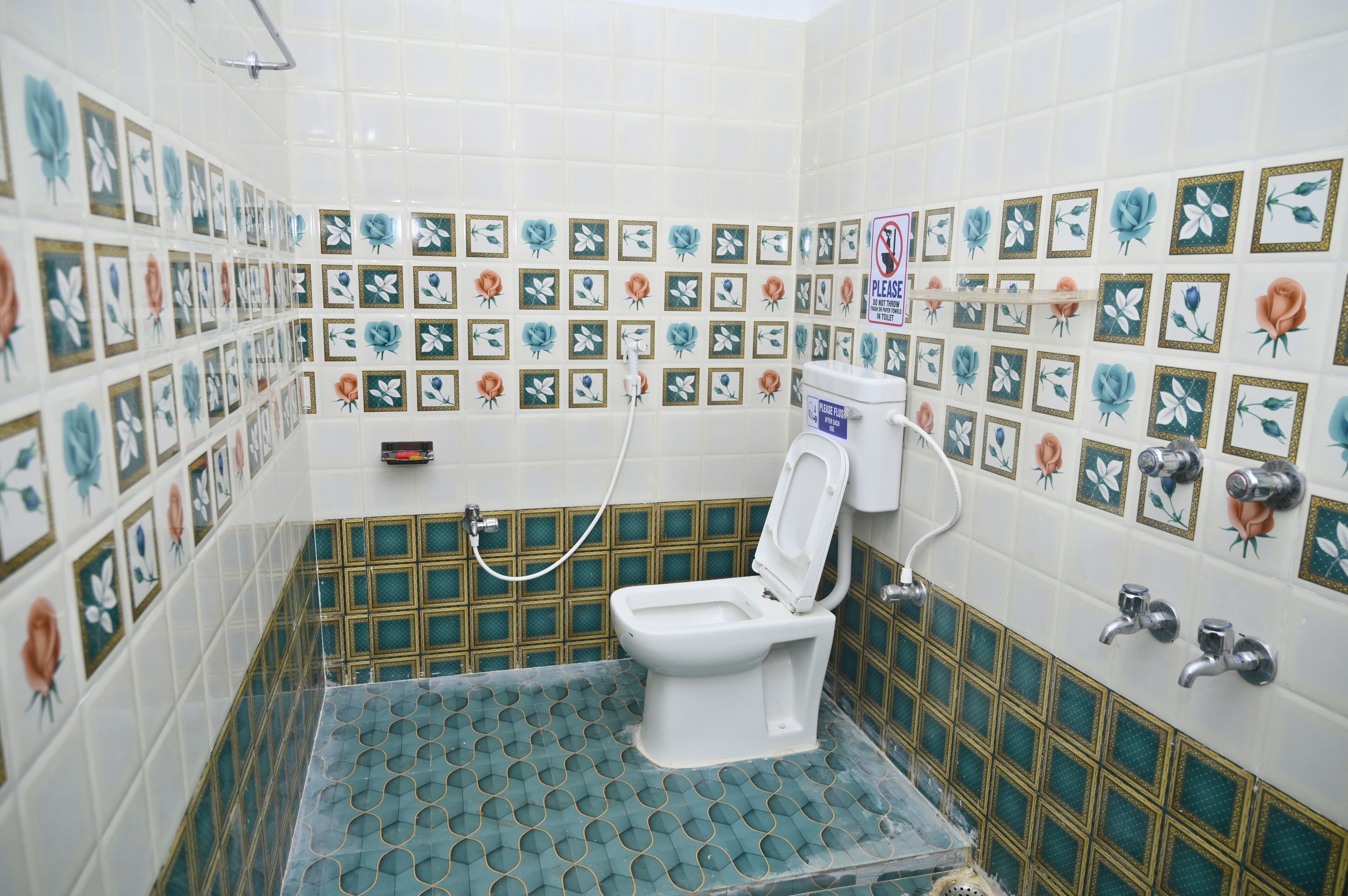 A bathroom with a toilet, shower, and tiled walls with floral patterns.