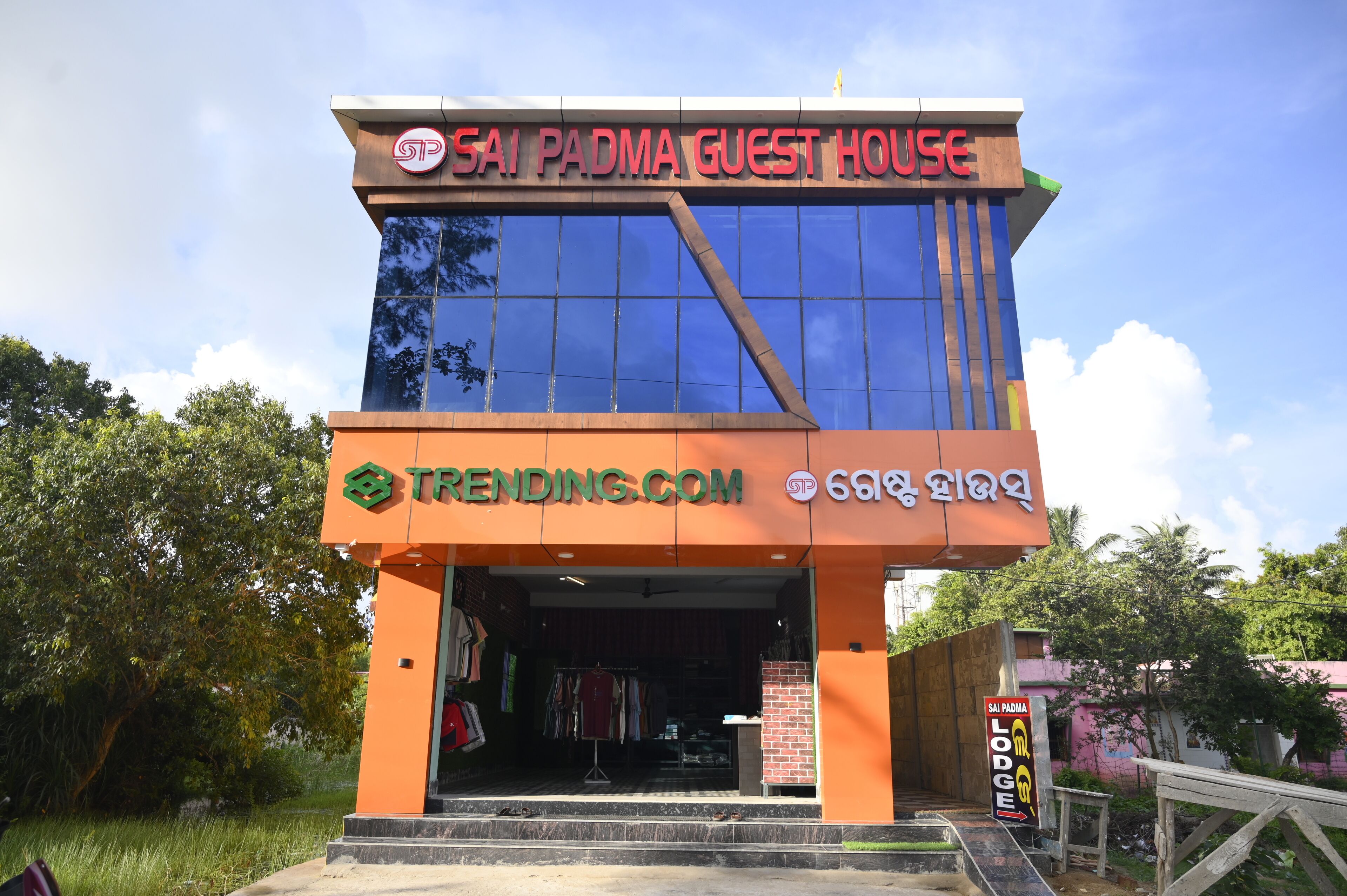 A building with a sign reading "Sai Padma Guest House" and a website address "trending.com".