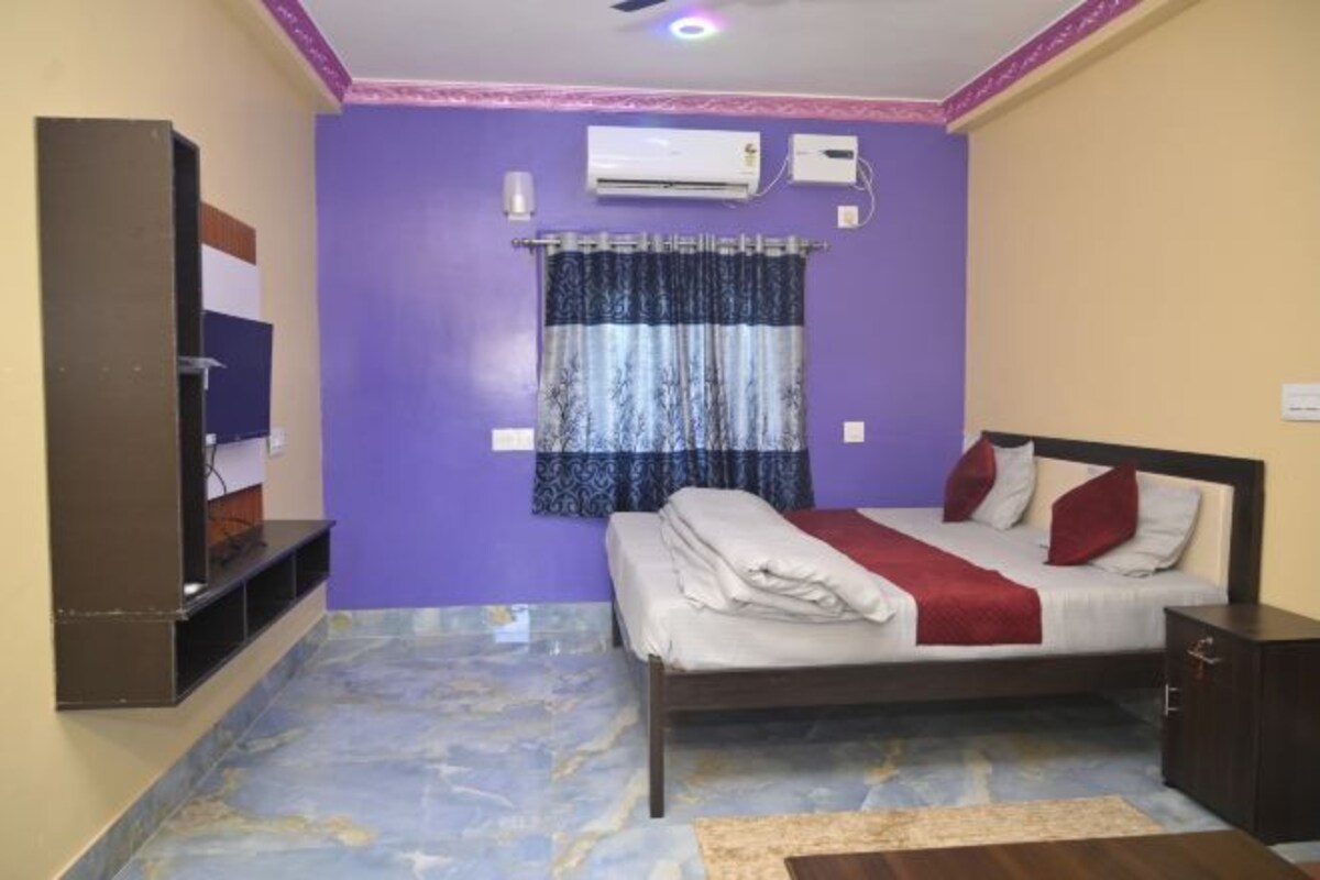 A bedroom with a bed, a TV, an air conditioner, and a window with curtains.