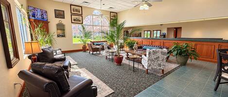 A spacious lobby with a seating area, a reception desk, and a large window offering a view.