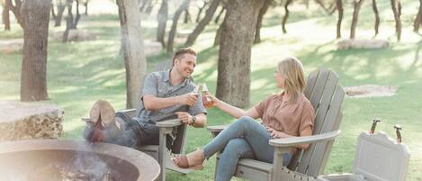 A couple sitting on outdoor patio chairs with a fire pit in the foreground.
