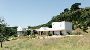 Un edificio moderno, bianco con tetto piatto, immerso in un paesaggio erboso e alberato.