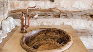Un muro in pietra rustica con un lavello in rame e un dispenser di carta.