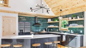 Een moderne keuken met een groot eiland, barkrukken en een uniek plafondontwerp.