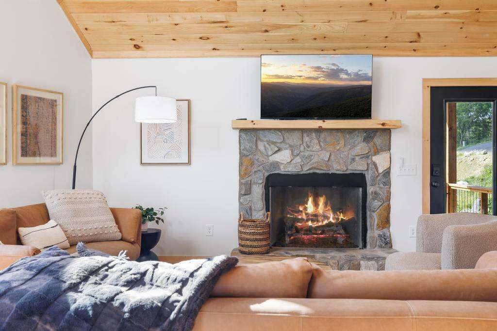 A cozy living room with a stone fireplace, a mounted TV, and a comfortable sofa.