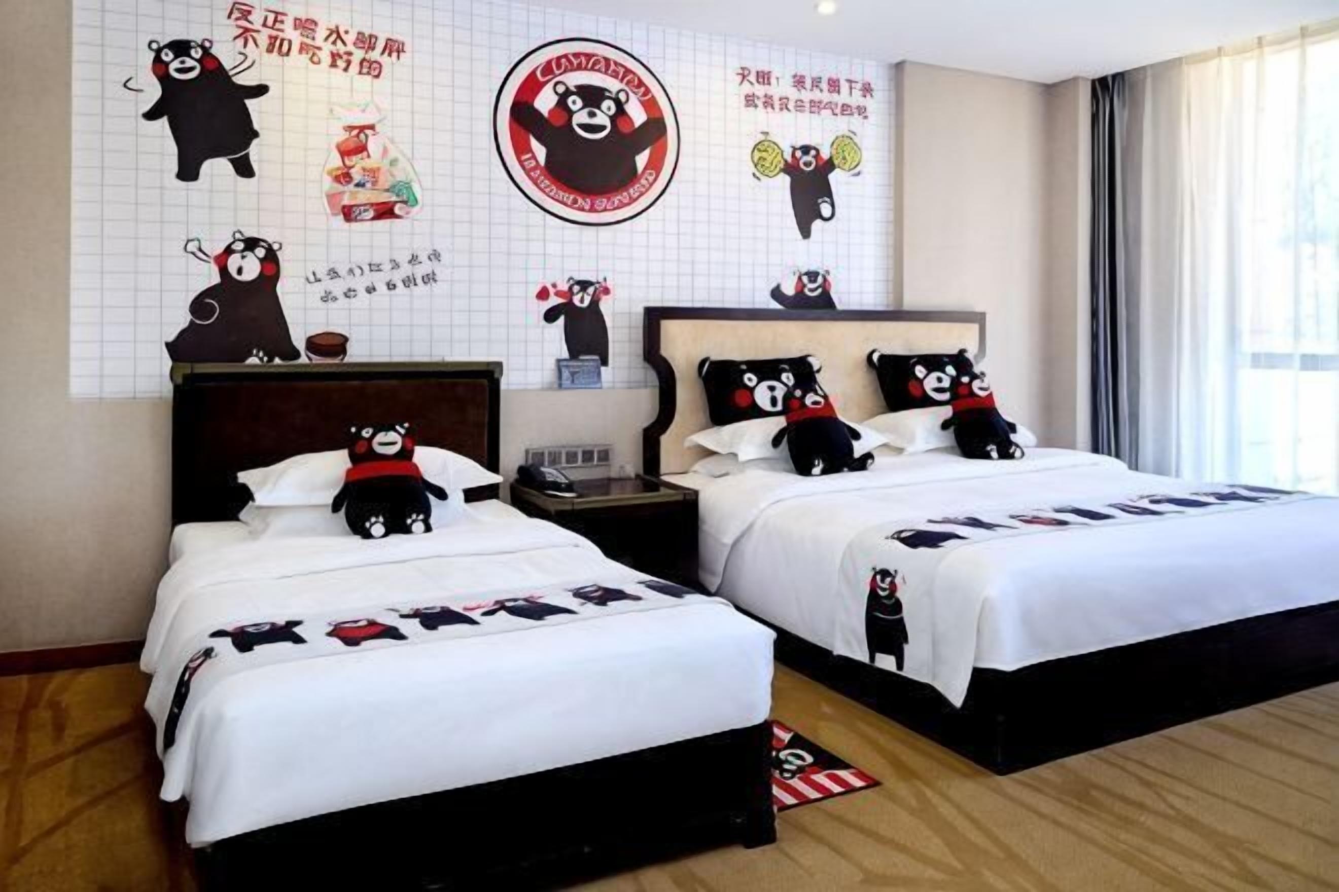 Une chambre d’hôtel avec deux lits, chacun agrémenté d’une couvre-lit sur le thème de l’ours, d’une grande horloge murale et d’une décoration représentant un ours.
