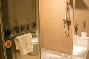 A glass-enclosed shower area with a towel hanging on the door, a toilet, and a wall with animal silhouettes.
