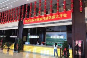 Un hall de hotel con una recepción, faroles rojos y una gran pantalla digital.